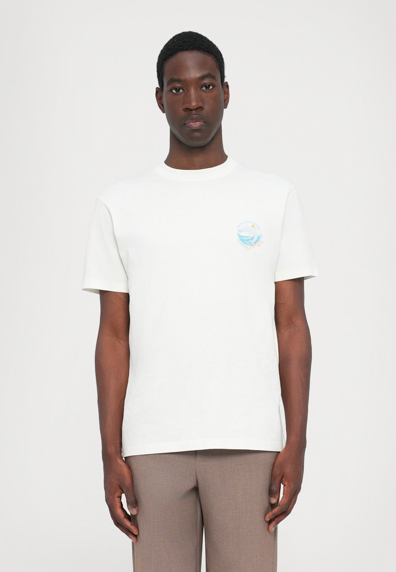 Hvid bomulds t-shirt med korte ærmer, rund halsudskæring og et lille blåt og orange grafik på brystet, der viser bølger og sol.