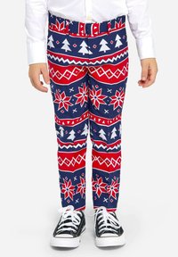 Mörkblå byxor med röda och vita festliga mönster inklusive träd och snöflingor, i kombination med svarta sneakers.