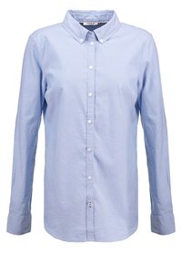 Chemise bleu clair à boutons avec un col structuré, des manches longues et des boutons blancs, fabriquée en coton doux.