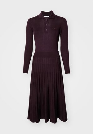 Long-sleeve, ribbed dress in dark purple with a polo collar, button front, and pleated skirt. Made of a knitted fabric.