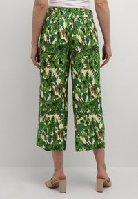 Pantaloni cropped a motivo floreale verde con cintura elastica, caratterizzati da tonalità di verde e marrone, realizzati in un tessuto leggero.