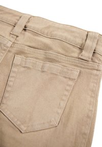 Beige corduroy fabric featuring a straight cut, five belt loops, and two back pockets with stitched detailing.