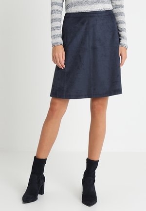 Jupe A-line en faux daim bleu marine avec une construction sans couture, longueur genou et une texture lisse. Complétée par un haut à rayures à manches longues.