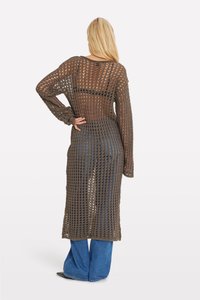 Cardigan lungo a maglia aperta di colore marrone scuro con una vestibilità ampia e squadrata. Presenta maniche lunghe e una trama trasparente e leggera. Indossato sopra jeans blu.