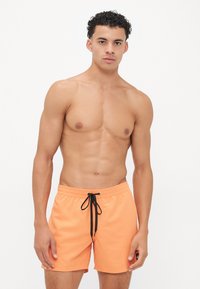Pantaloni scurți de înot portocalii, cu un talie elastică, un șnur negru și un mic patch cu logo pe piciorul stâng. Material neted și ușor.
