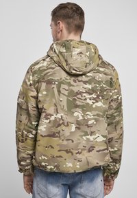 Kamuflagejakke i nuancer af Grøn, Brun og Creme, med hætte, elastiske manchetter og en afslappet pasform, lavet af struktureret stof.