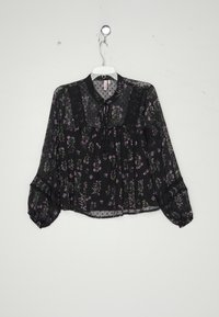 Blusa nera trasparente con un motivo floreale in viola e verde, vita arricciata, maniche lunghe a sbuffo e dettagli in pizzo al colletto e ai polsini.