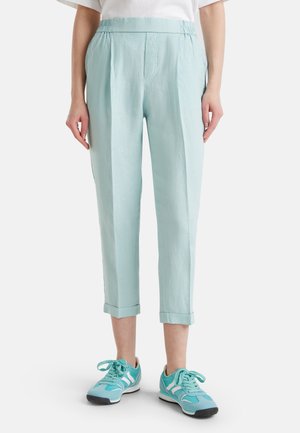 Pantalones azul claro, mezcla de lino, ajustados con cintura elástica y puños enrollados. Combinados con zapatillas turquesas.