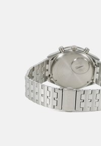 Silver stainless steel watch with a linked bracelet, featuring a round case, chronograph buttons, and an engraved logo on the clasp.
