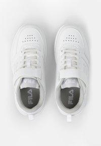 Valkoiset urheilukengät nahkaisella päällisellä, rei'itetyillä yksityiskohdilla ja nauhakiinnityksellä. Varustettu tarranauhalla ja harmaalla sisäpohjalla, jossa on logo.