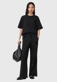 T-shirt oversize di cotone nero con logo, abbinato a pantaloni della tuta neri coordinati con vita con elastico e bottoni laterali.