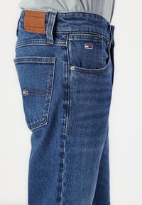 Modré džínové kalhoty s rovně střihem, s koženou nášivkou v pase a malým logem na zadní kapse. Klasický design s pěti kapsami.