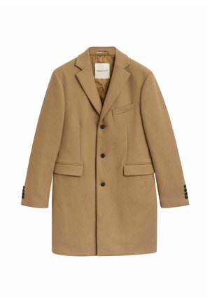 Bruine wollen jas met een ingezette reverskraag, twee voorkantzakken, een borstzak en zes knoopaccenten op de manchetten. Gevoerd interieur.