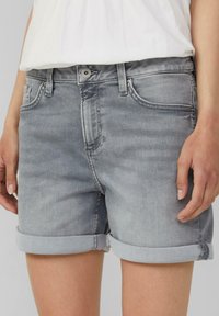 Shorts en denim gris avec ourlets roulés, design à cinq poches et fermeture à bouton métallique. Le tissu présente un léger dégradé, offrant un look décontracté.