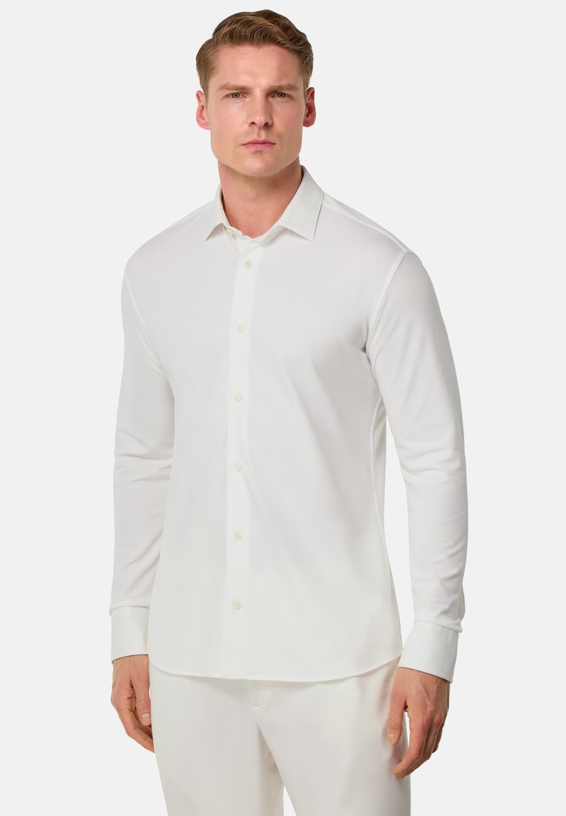 Camicia bianca a maniche lunghe con bottoni, realizzata in tessuto liscio, caratterizzata da un colletto classico, taglio dritto e semplici dettagli con bottoni.