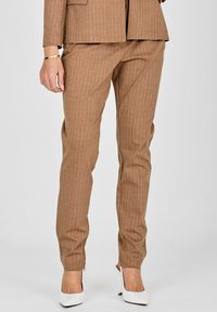 Brah v črte hlače iz teksturirane tkanine, ki imajo prilegajoč kroj in zožen dizajn nog, v kombinaciji z belimi visokimi petkami.