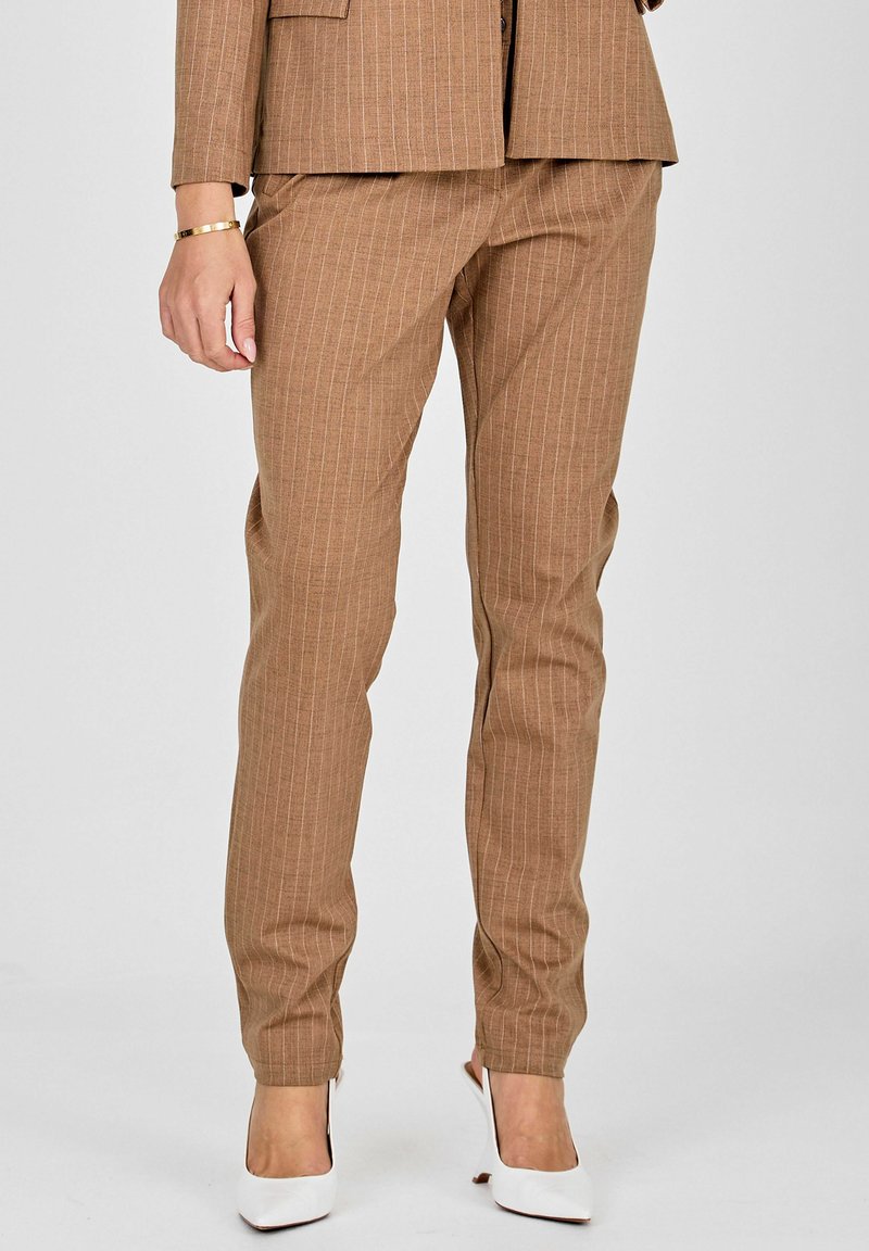 Brah v črte hlače iz teksturirane tkanine, ki imajo prilegajoč kroj in zožen dizajn nog, v kombinaciji z belimi visokimi petkami.