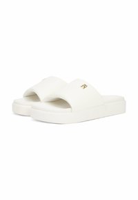 Sandalias deslizables blancas con un material superior texturizado, suela plana tipo plataforma y un sutil acento de logo dorado en la parte delantera.