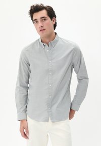 Lichtgrijze button-up shirt met een klassieke kraag, lange mouwen en een subtiele textuur. Gecombineerd met off-white broeken, wat een casual stijl laat zien.