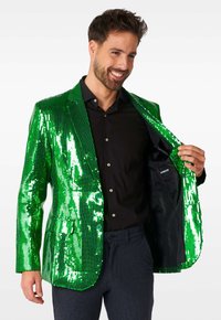 Blazer verde con paillettes, dalla texture lucida e design aderente. Caratterizzato da un colletto a punte, due bottoni e abbinato a una camicia nera.