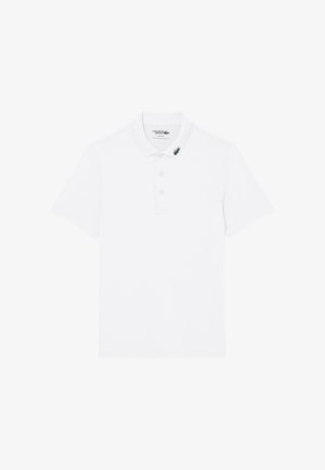 Wit poloshirt met korte mouwen, een kraag en drie knopen, met een klein groen krokodillenlogo op het linkerpunt van de kraag.