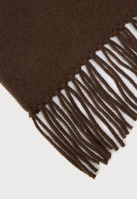 Καφέ πλεκτό κασκόλ με κρόσσια στις άκρες, που παρουσιάζει ομαλή υφή και ομοιόμορφο σχέδιο σε όλο το μήκος. Οι λεπτομέρειες στις άκρες τονίζουν τα κρόσσια.