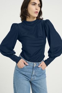 Marinblå langermet topp med samlet sidene detaljer og puffede ermer, kombinert med høyt liv lys blå jeans. Jevn tekstur.