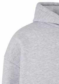 Švarkas-hoodie šviesiai pilkos spalvos, pagamintas iš minkštos, tekstūruotos medžiagos. Turi gobtuvą ir kritimo pečių dizainą, suteikiantį laisvą prigludimą.