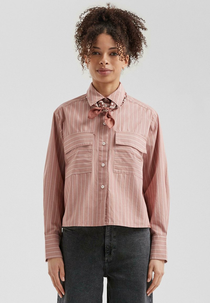 Chemise à rayures rose clair avec deux poches poitrine, manches longues et une écharpe florale au cou. Tissu doux et tissé avec une coupe décontractée.