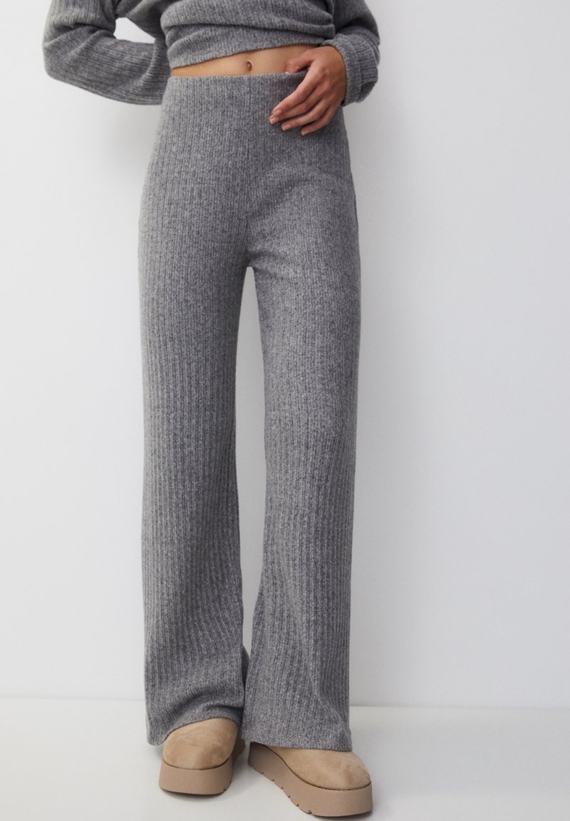 Grijze geribbelde gebreide flarebroek met een hoge taille en een zachte textuur, gecombineerd met beige plateauschoenen.