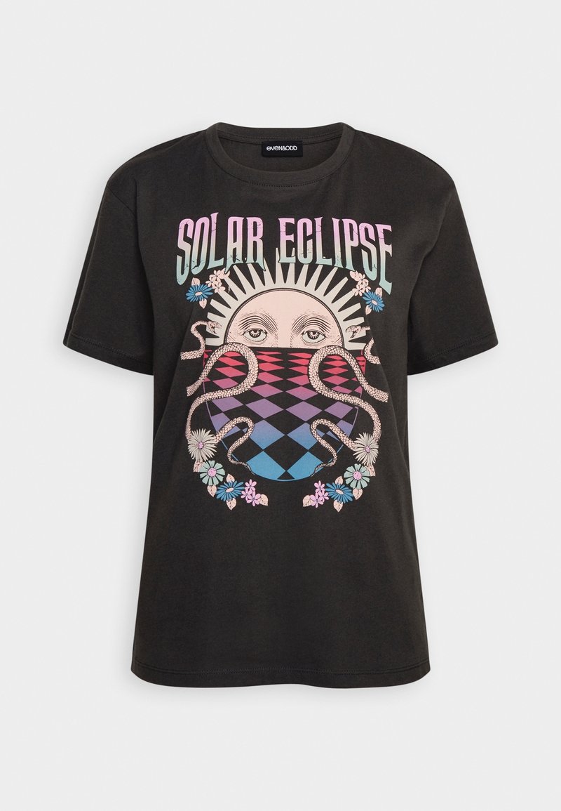 T-shirt en coton noir avec un graphisme "Éclipse Solaire" comportant un soleil stylisé et des motifs floraux dans des nuances de rose, bleu et violet. Manches courtes.
