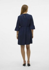 Marinblå klänning med insvängd midja, trekvartslånga utsvängda ärmar och detalj med nyckelhål bak, tillverkad av mjukt tyg. Slät textur.