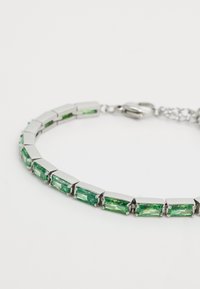 Bracelet en argent clair avec des pierres vertes rectangulaires à surface facettée, reliées par des accents métalliques, créant un motif géométrique.