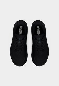 Ζευγάρι μαύρα αθλητικά παπούτσια HOKA με κορδόνια, σε θέα από πάνω, σε λευκό απλό φόντο.