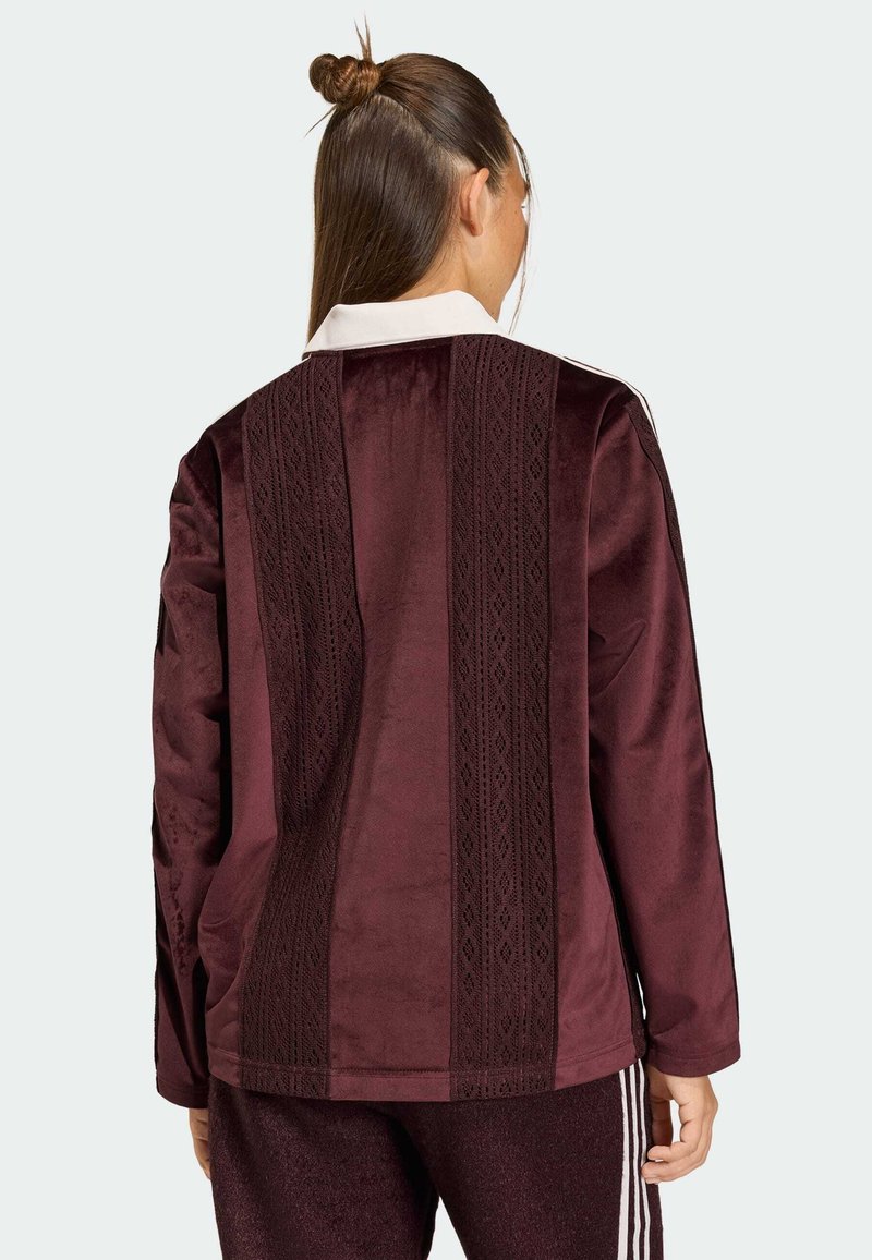Bordeaux velours jasje met lange mouwen, witte kraag en gestructureerde verticale strepen. Gladde oppervlakte met complexe patroon details.