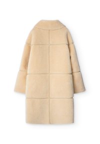 Beige fårskinnsjacka med boxig design, stor krage och vida ärmar. Tyget har en mjuk textur med fyrkantiga paneldetaljer.