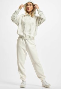 Hettegenser og matchende joggebukser i off-white med et subtilt tie-dye-mønster. Mykt stoff, avslappet passform, ribbet mansjetter og elastisk midjebånd.