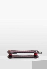 Kolfiberverktyg med en smal kropp, röda accenter, metalliska ändar och en kompakt design. Utrustad med ett runt vred för justering.