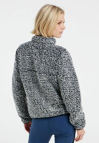 Fleece-Pullover im schwarz-weißen Melange-Muster, mit steigendem Kragen, lockerer Passform und strukturierter Oberfläche.