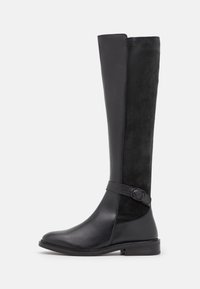 Bottes en cuir noir montant jusqu'aux genoux avec une finition lisse et des panneaux en daim, dotées d'une sangle latérale avec une boucle ronde et d'un talon bas et épais.