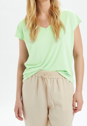 Lys grøn, kortærmet V-hals top lavet af blødt materiale, parret med lys beige bukser med elastisk talje og snøre detalje.