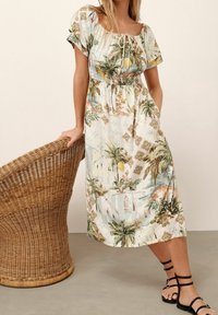 Robe midi à motif floral avec manches courtes froncées, encolure à cordon, et taille élastique. Tissu léger et lisse aux couleurs pastel douces.