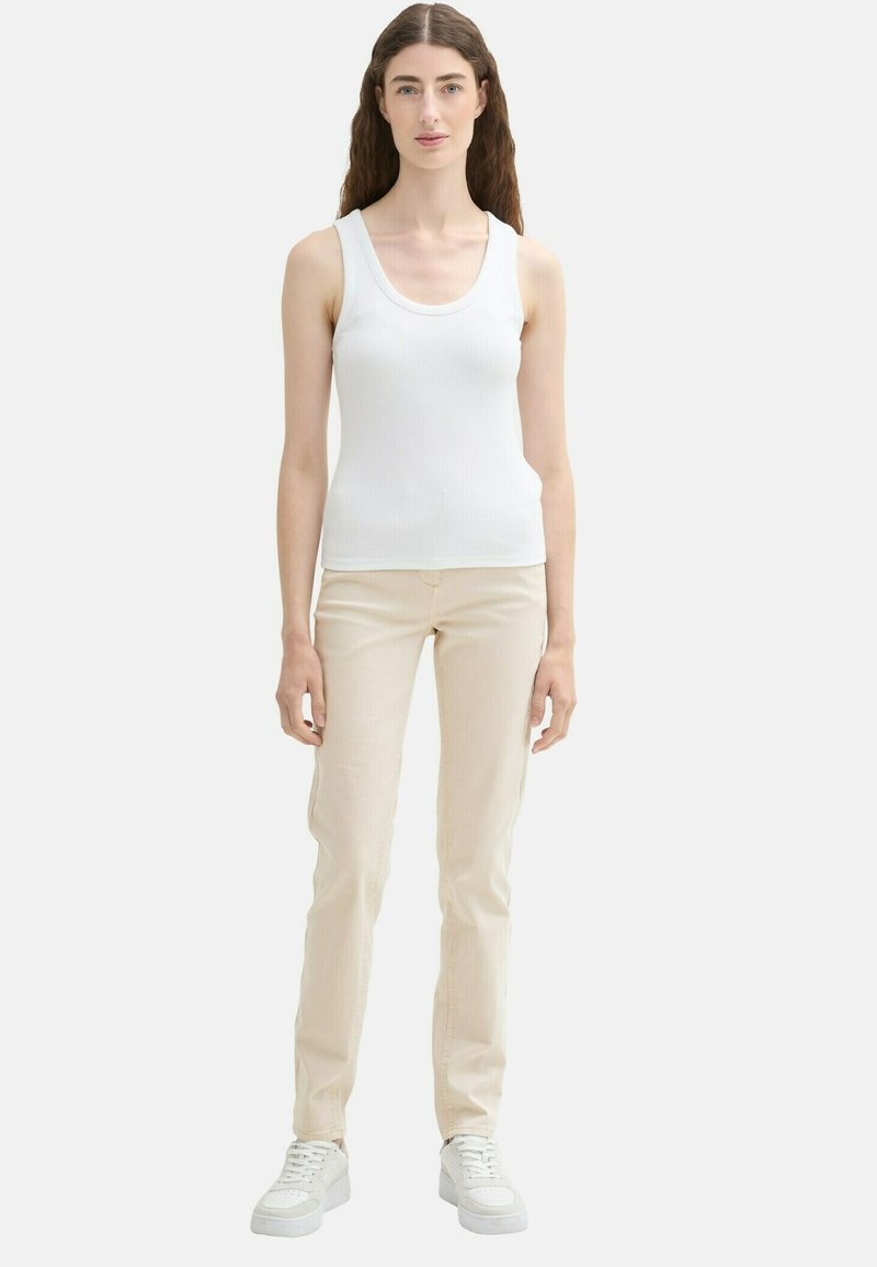 Biały podkoszulek z żebrowanej tkaniny w połączeniu z dopasowanymi beżowymi spodniami i białymi trampkami, prezentujący smukłą sylwetkę i minimalistyczny design.