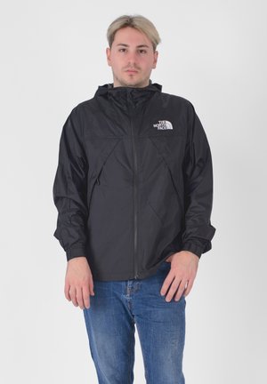 Giacca a vento nera con cerniera completa, cappuccio e polsini elasticizzati. Presenta un logo bianco sul lato sinistro del petto e un tessuto liscio e leggero.