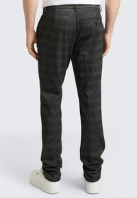 Szare kratkowane spodnie o dopasowanym kroju, wyposażone w dwie tylne kieszenie i zapięcie na guzik, zestawione z białymi trampkami.