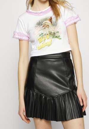 Camiseta corta blanca con borde de encaje rosa, con un gráfico de Santa y el texto "¡Es un día festivo!" Combinada con una falda plisada de cuero sintético negra.