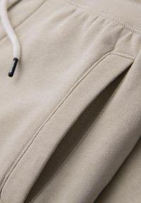 Beige bavlněné šortky s elastickým pasem, s tkaničkou a bočními kapsami. Hladká textura s jemnými švy.