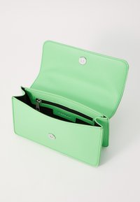 Portafoglio in pelle verde menta con chiusura a scatto, con una tasca interna nera e accessori in argento. L'interno è dotato di scomparti per schede.