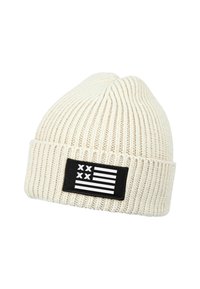 Knit beanie in off-white with ribbed texture; features a black patch displaying a stylized flag with white stripes and black accents.