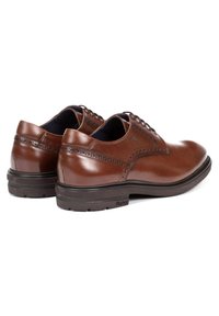 Zapatos de vestir de cuero marrón con una textura suave, puntera redondeada, perforaciones decorativas y suela de goma resistente, que exhiben un diseño pulido.